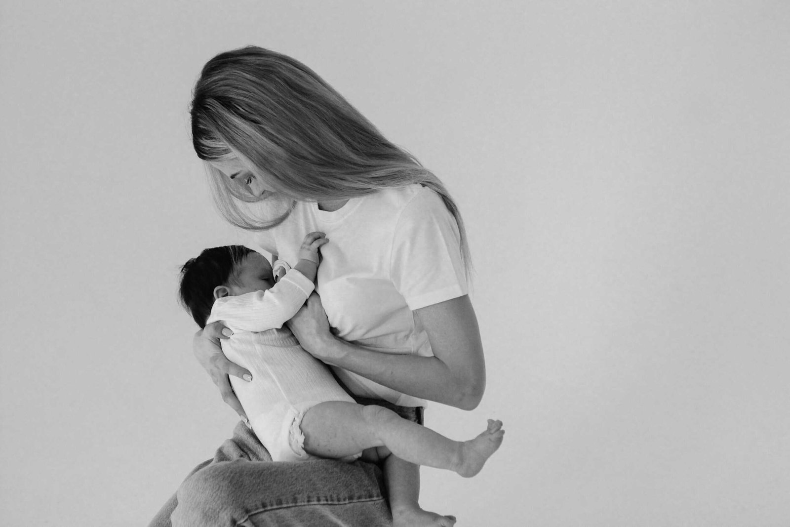 A touching black and white image of a mother tenderly breastfeeding her baby.