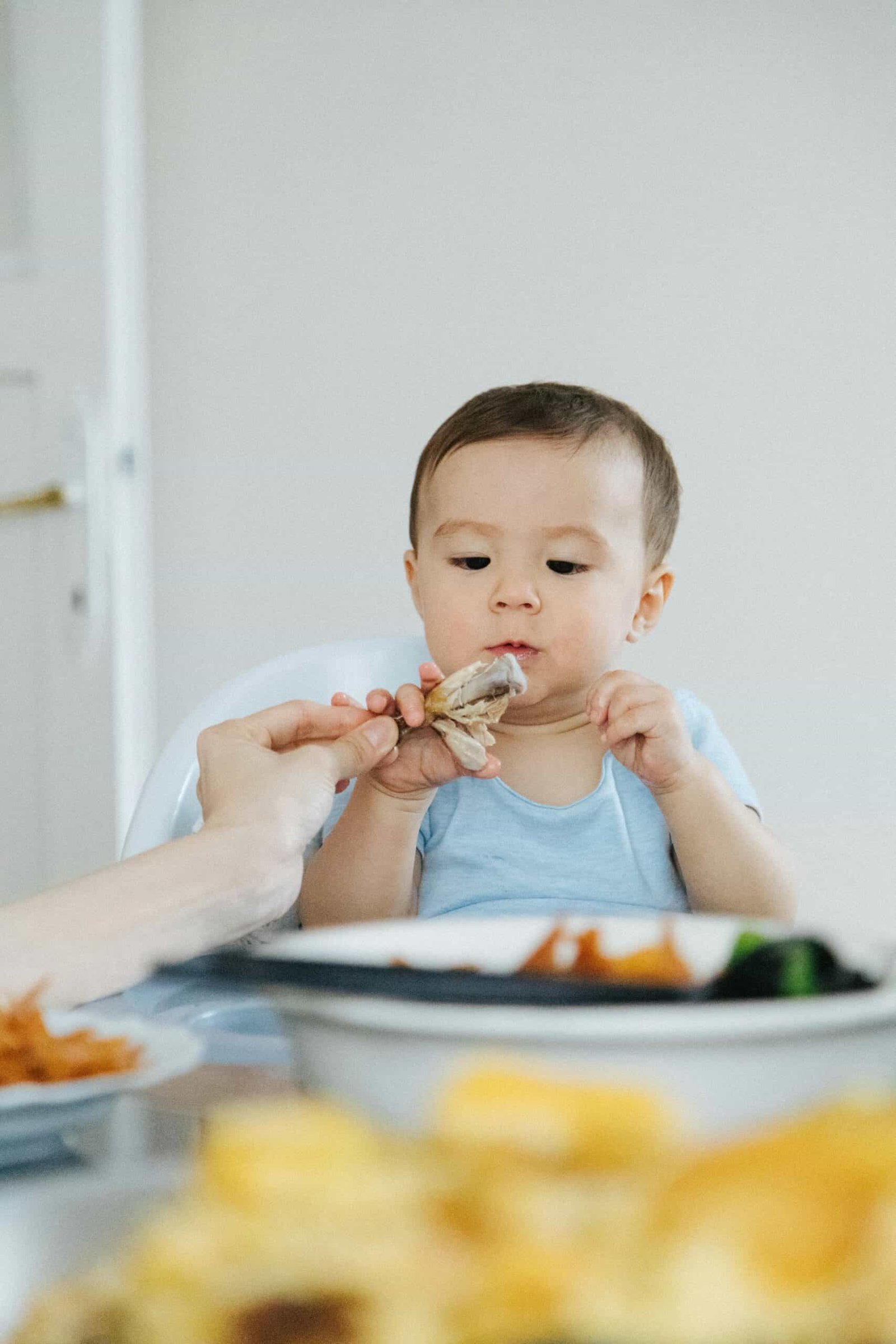 Adorable baby eating at the dining table, an intimate moment captured indoors.