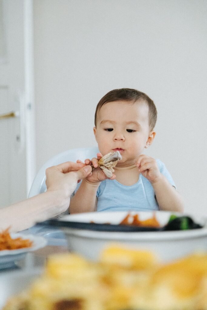 Adorable baby eating at the dining table, an intimate moment captured indoors.